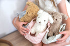 Two children holding plush puppies in striped fabric carriers