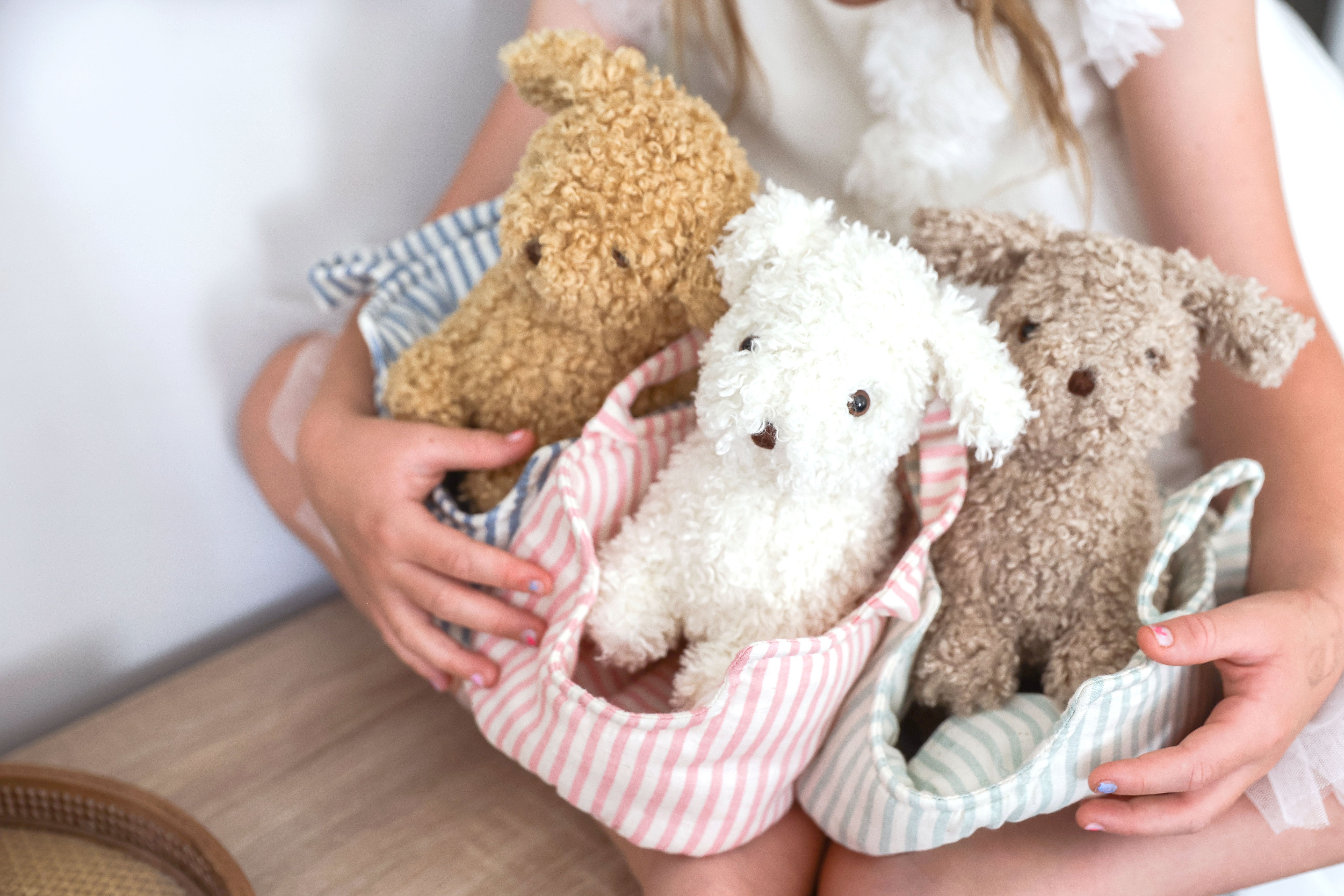 Two children holding plush puppies in striped fabric carriers