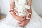 Child in a white dress holding Marshmallow puppy in its pink striped carrier