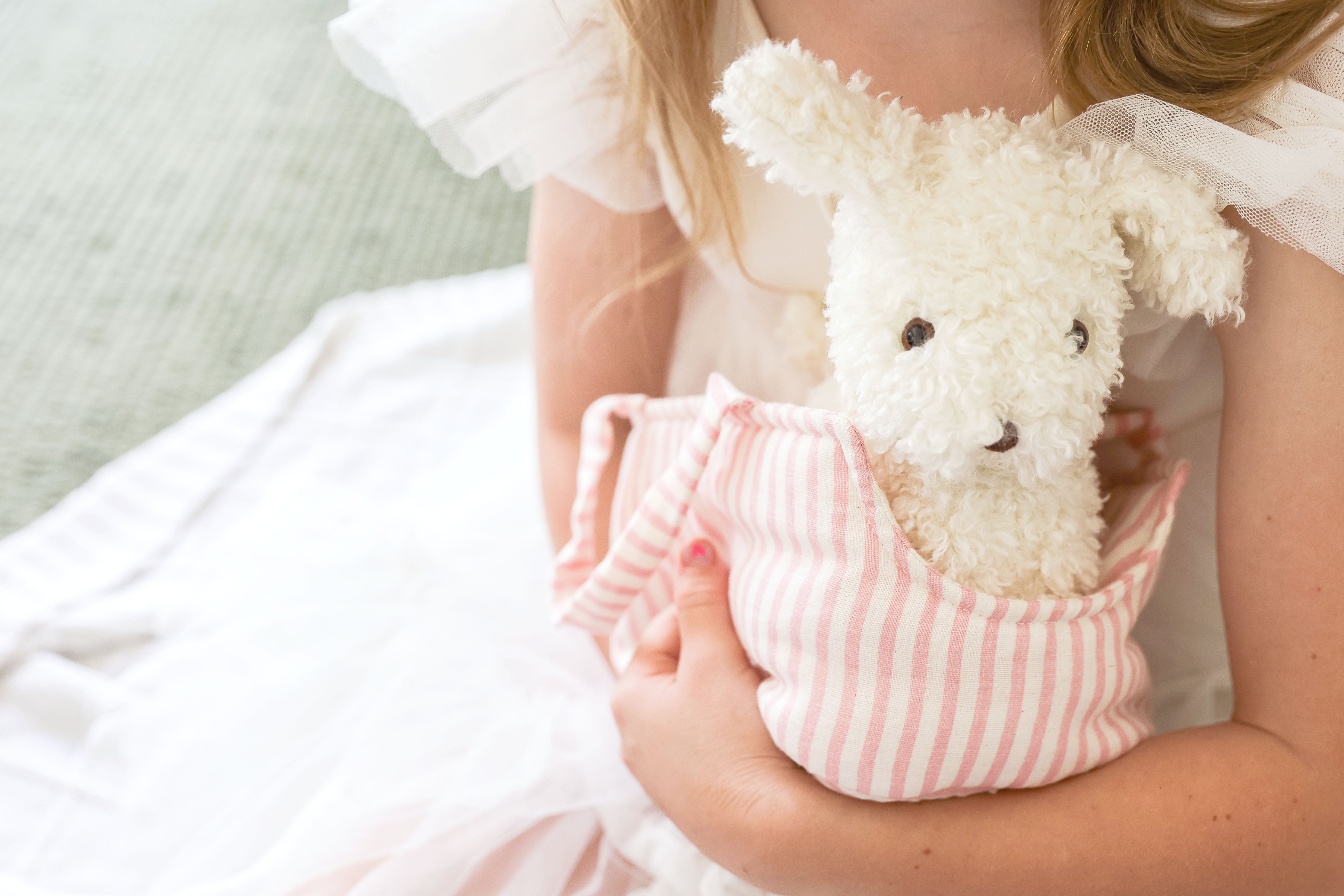 Child cuddling the Marshmallow puppy plush in its carrier