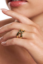 Model wearing the gold Helena knot ring, hand raised near her face.