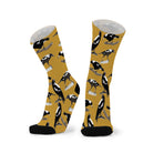 Pair of warm mustard socks with black toes, printed with black and white magpies strutting and swooping.