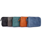 Flap-front cross body bags lined up in black, taupe, green, tan and midnight blue