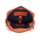 The cognac bag open, showing the dark navy lining, the tablet sleeve tab and a stamped leather tab