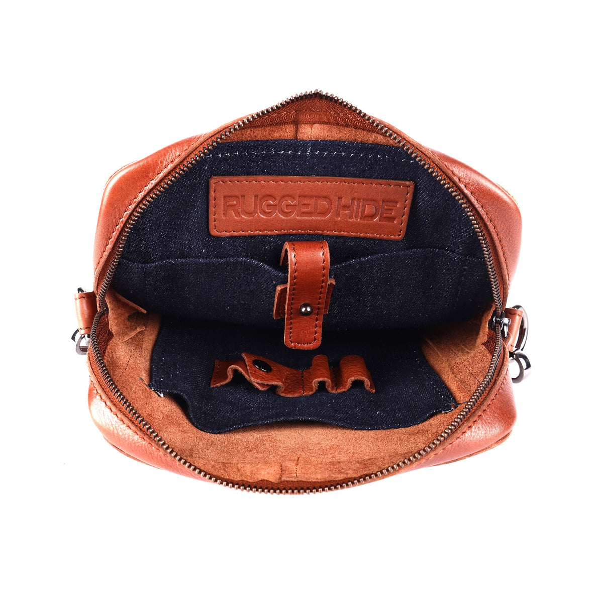 The cognac bag open, showing the dark navy lining, the tablet sleeve tab and a stamped leather tab