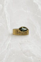 Wide fluted gold band ring with an olive-green marquise stone set flat into the front