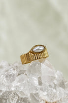 Wide fluted gold band ring with a white pearl marquise stone set flat into the front