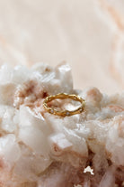 Slim gold band ring shaped in a soft wave and set with small clear stones