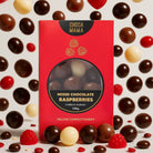 Mixed chocolate raspberries box surrounded by scattered chocolates and raspberry jellies