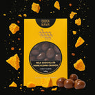 Honeycomb crunch box on black with scattered honeycomb shards and chocolates