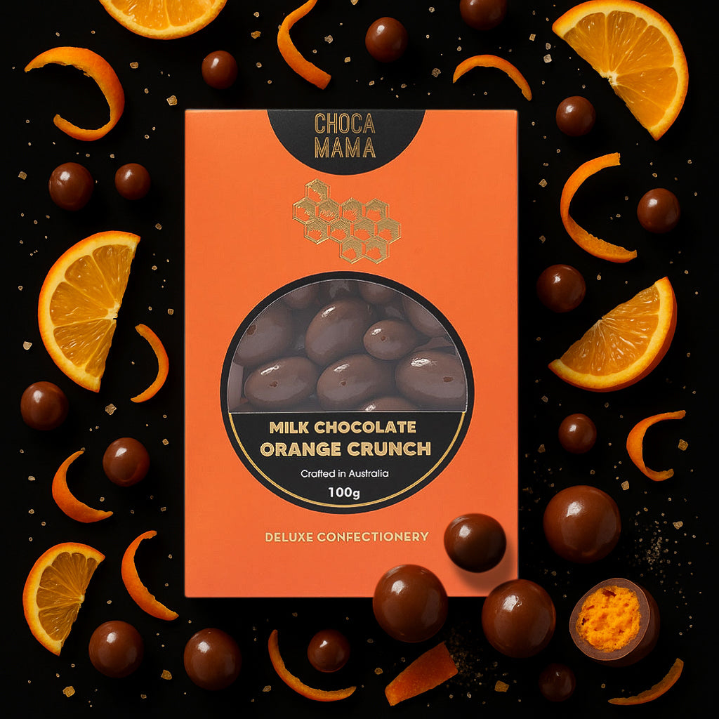 Orange crunch box on black among orange slices, curls of peel and chocolate balls, one cut open to show an orange centre