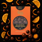 Orange crunch box on black among orange slices, curls of peel and chocolate balls, one cut open to show an orange centre