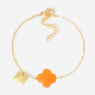 Fine gold chain bracelet with an orange glass four-leaf clover and a small engraved gold tag
