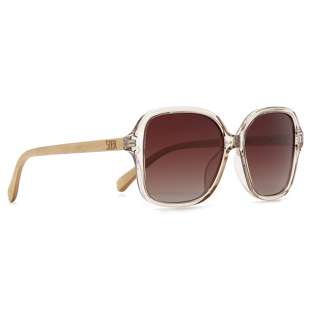 Three-quarter view of the Scarlett sunglasses: oversized square champagne frame, brown gradient lenses, maple arms
