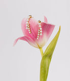 The earrings resting on the petal of a pink lily