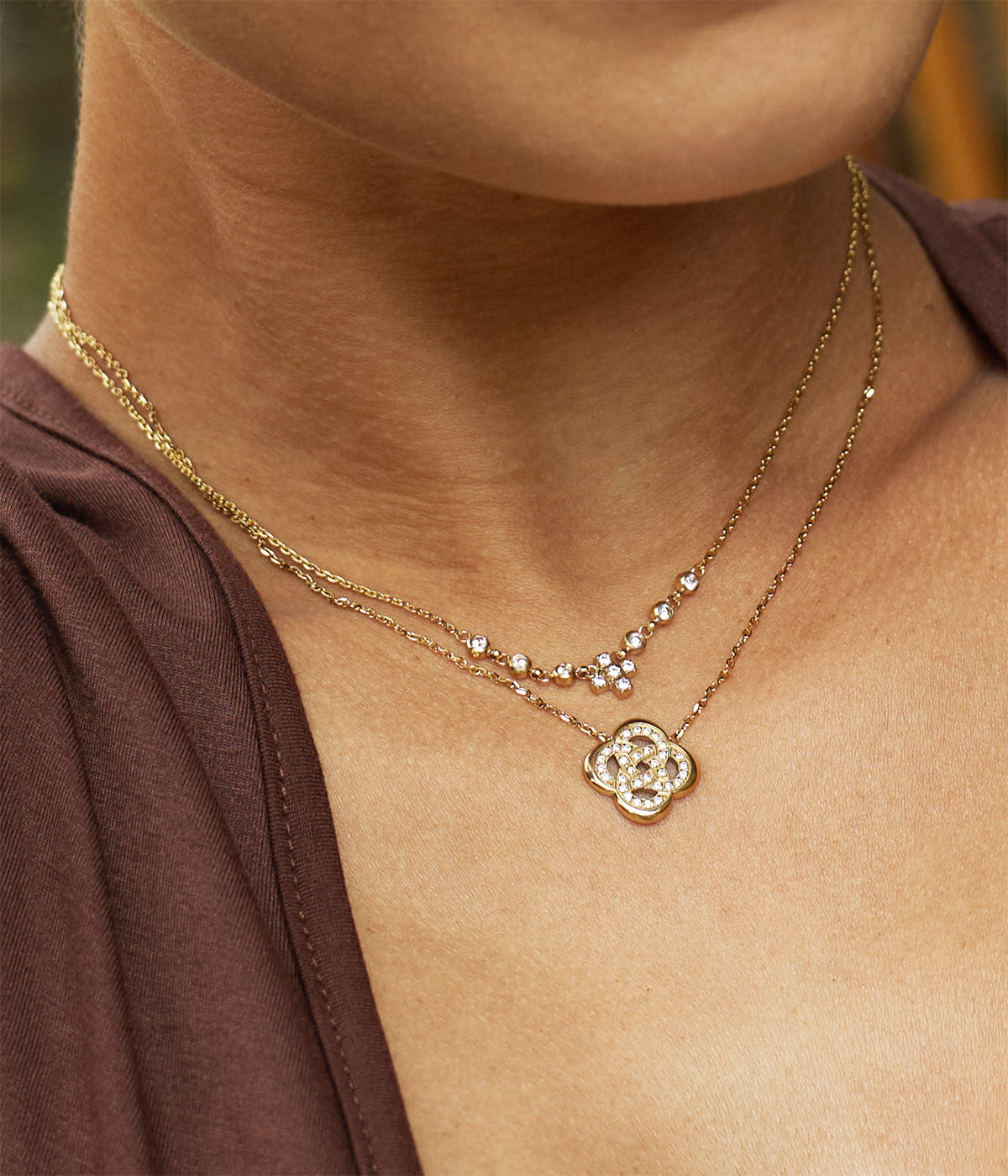 Model wearing the crystal cross necklace against a brown top