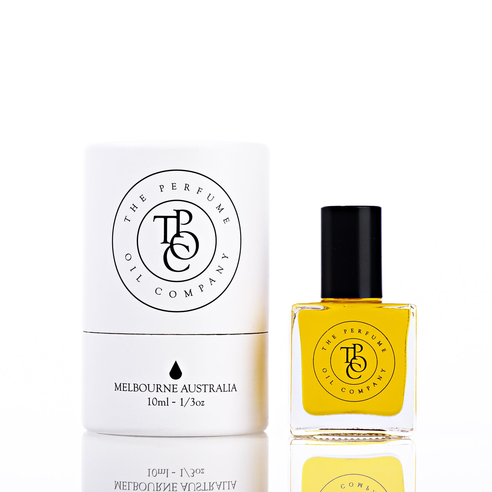 The Perfume Oil Company white gift cylinder beside a 10 ml bottle of deep amber-gold perfume oil