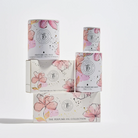 The Perfume Oil Collection floral gift boxes stacked, with pink blossom illustrations