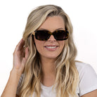 A woman with long blonde hair wearing the Vibe sunglasses