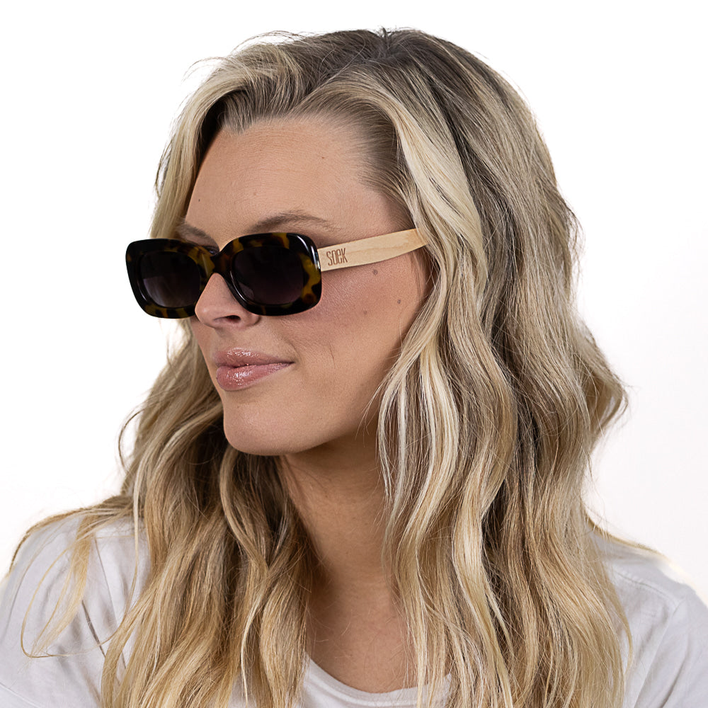 A woman with long blonde hair wearing the Vibe sunglasses, turned to the side