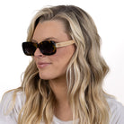 A woman with long blonde hair wearing the Vibe sunglasses, turned to the side