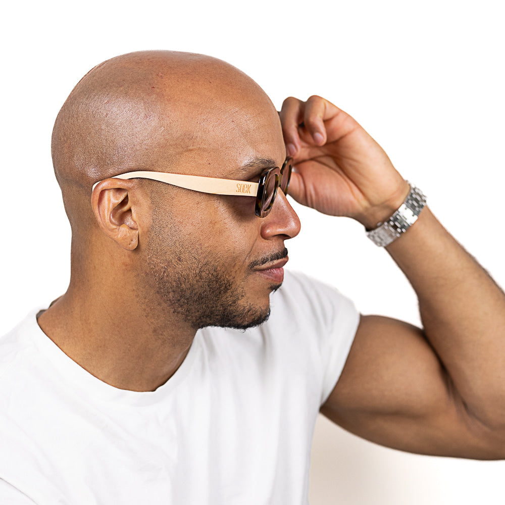A man adjusting the Vibe sunglasses as he wears them, in profile