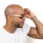 A man adjusting the Vibe sunglasses as he wears them, in profile