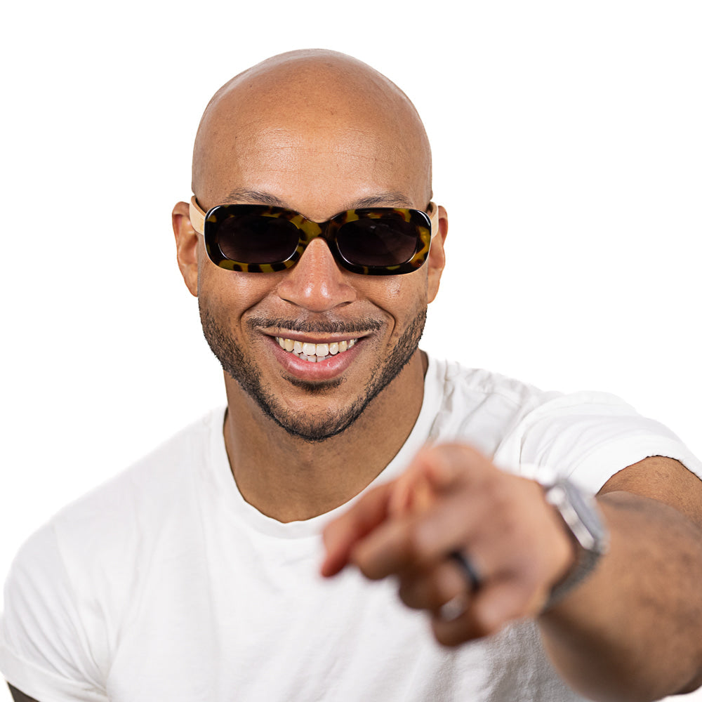 A man smiling and pointing, wearing the Vibe sunglasses