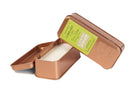 Copper-coloured travel tin candle open to show the white wax, its lid bearing a lime green Library label for Oscar Wilde: cedarwood, thyme, basil.