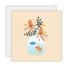 Square peach card with a kingfisher on a glass jar of banksias and wattle, a goldfish and a paper boat in the water, on a white envelope