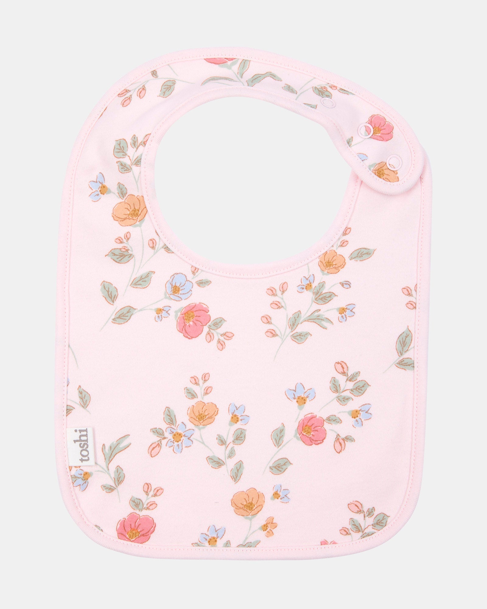 Toshi baby bib in pale pink cotton with a scattered floral print of coral, peach and blue blooms