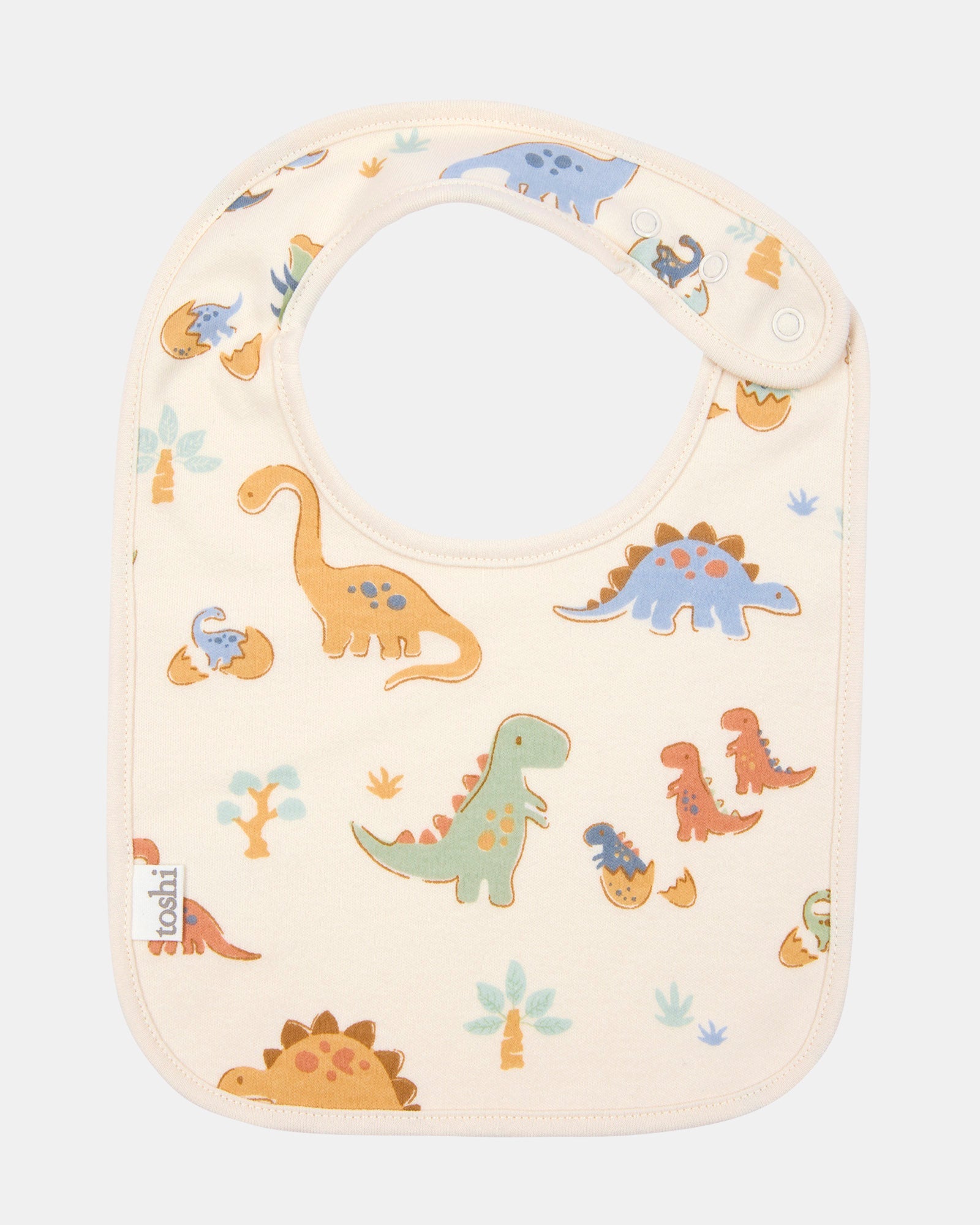 Toshi baby bib in cream cotton printed with dinosaurs in blue, green and rust
