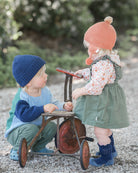 Two toddlers outdoors with a vintage trike, one in the navy Rover beanie