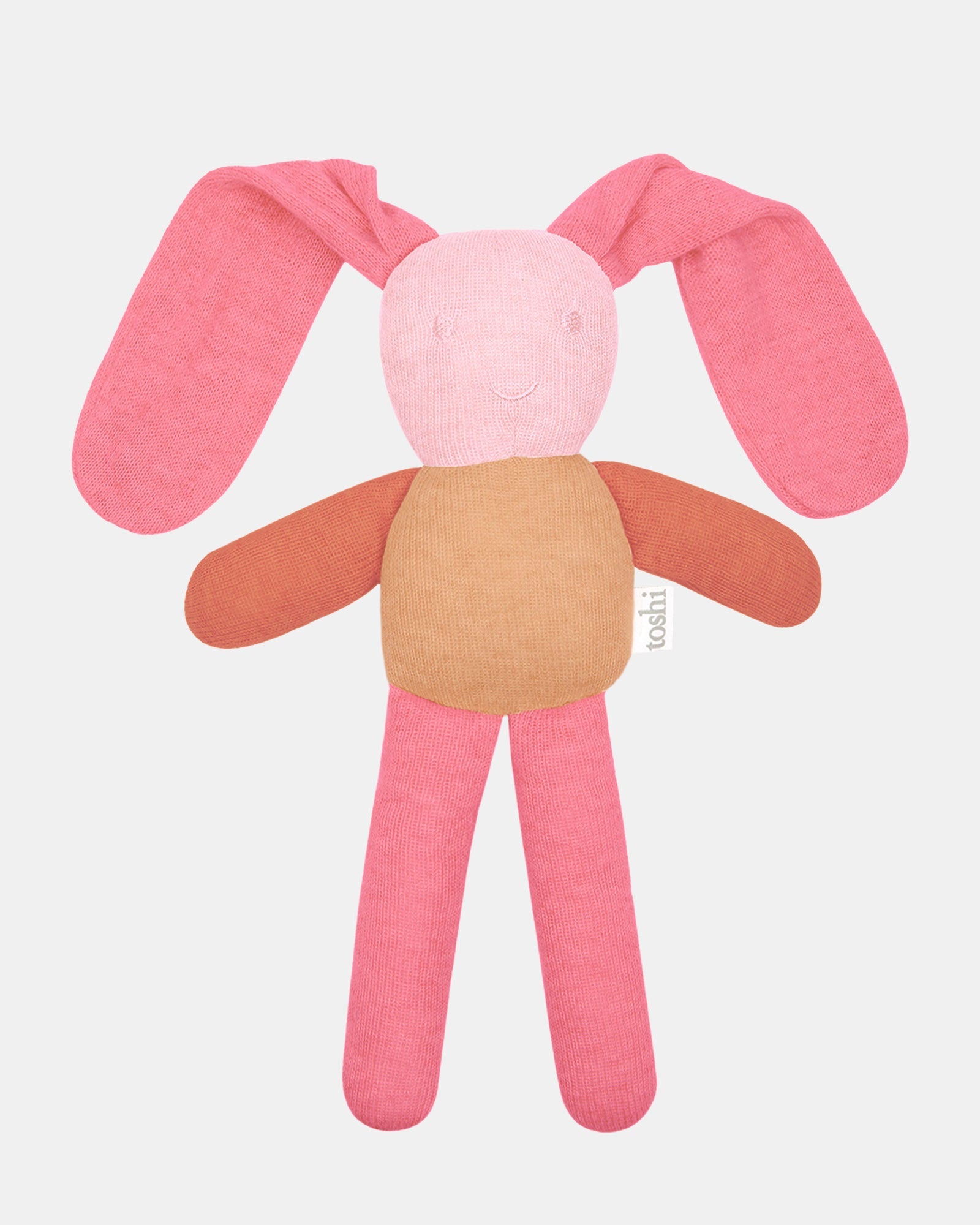 Toshi Bunny Bobby knitted comforter in misty rose — long floppy coral ears, a soft pink face with an embroidered smile, rust arms and pink legs
