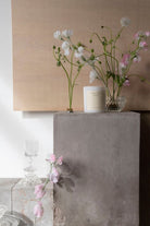 The Sweet Pea candle on a concrete plinth with sweet peas in glass vases.