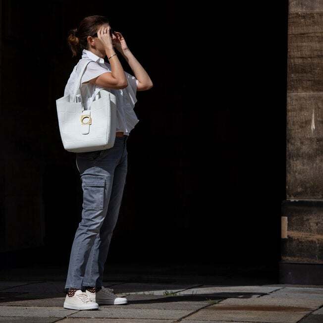 Woman in the street wearing Hosier sneakers with a white handbag