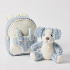 Pale blue curly plush backpack with cream panels and paw prints on the front pocket, the matching blue and cream puppy sitting beside it