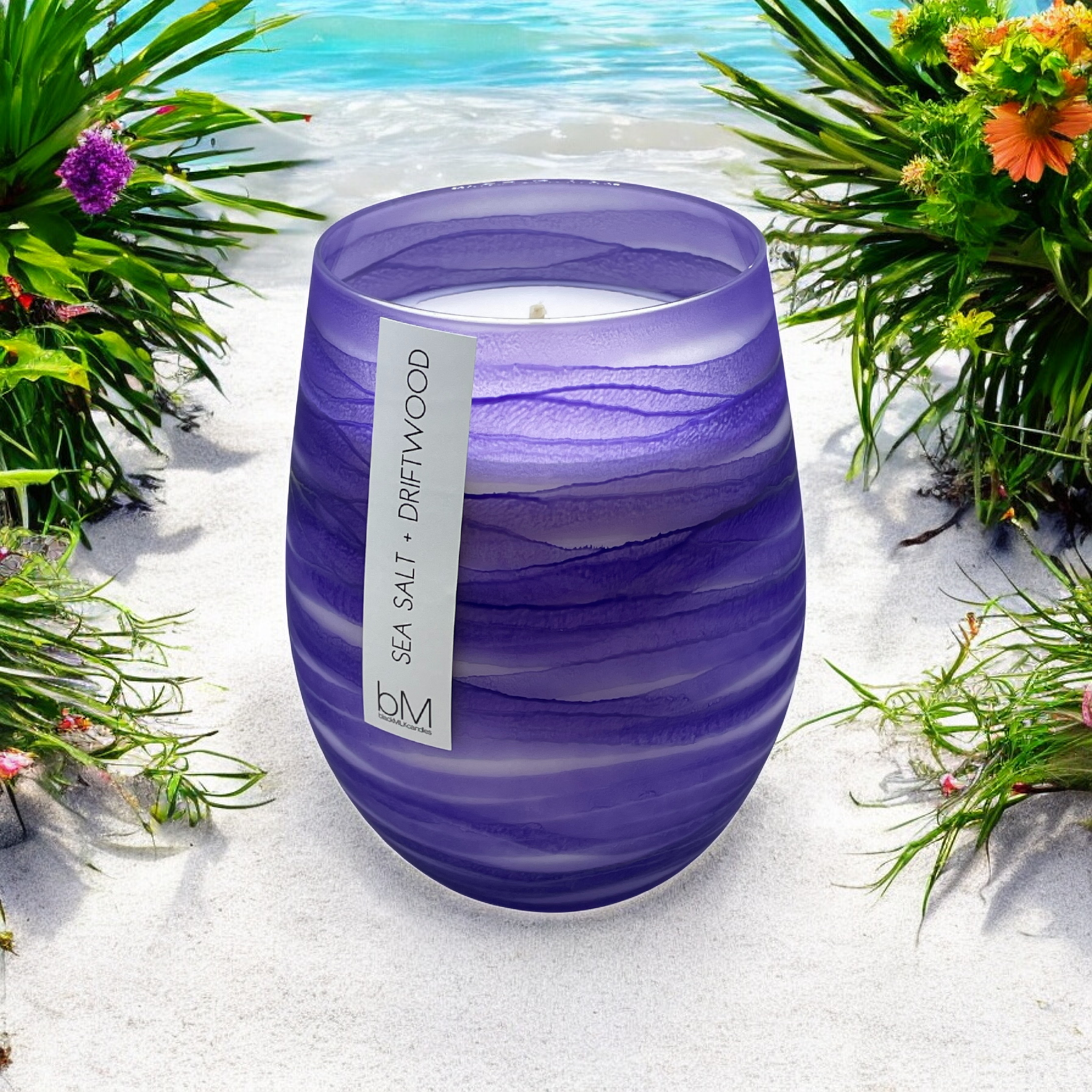 Wave Purple Sea Salt and Driftwood candle on white sand with beach grasses and the sea beyond