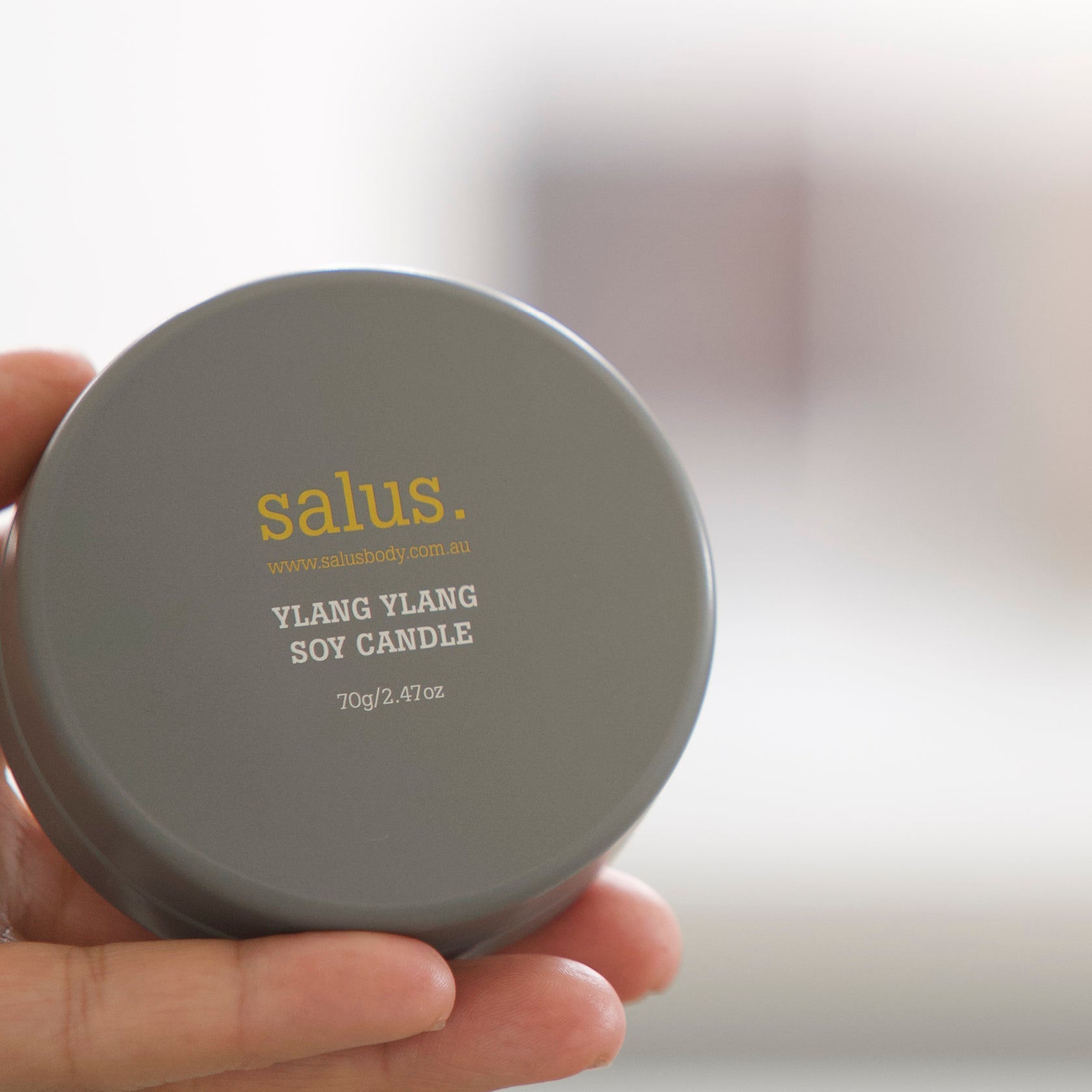 Hand holding the lidded Salus Ylang Ylang Soy Candle travel tin