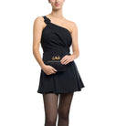 Model in a black one-shoulder dress holding the black clutch in front of her