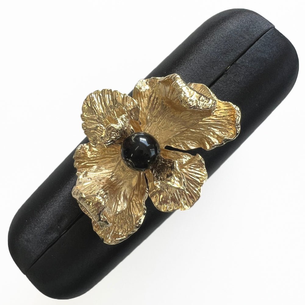Top view of the clutch lying at an angle, the orchid clasp in the middle