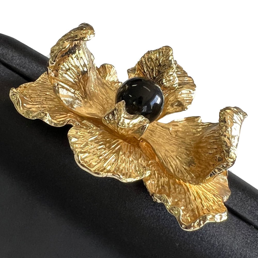Close-up of the textured gold orchid petals around a glossy black bead