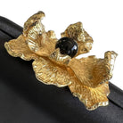 Close-up of the textured gold orchid petals around a glossy black bead