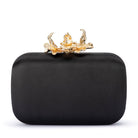 Black satin clutch from the front, a gold orchid clasp on top