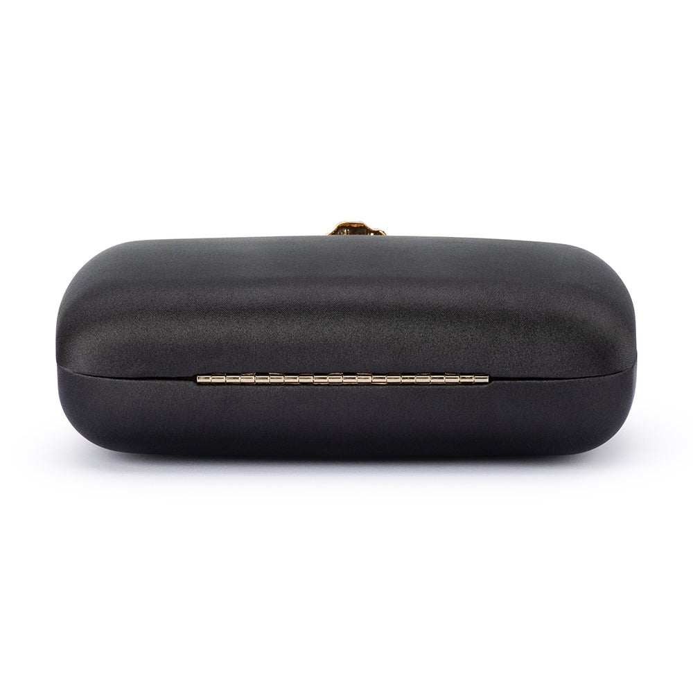 Back of the black satin clutch, a slim gold hinge along the seam