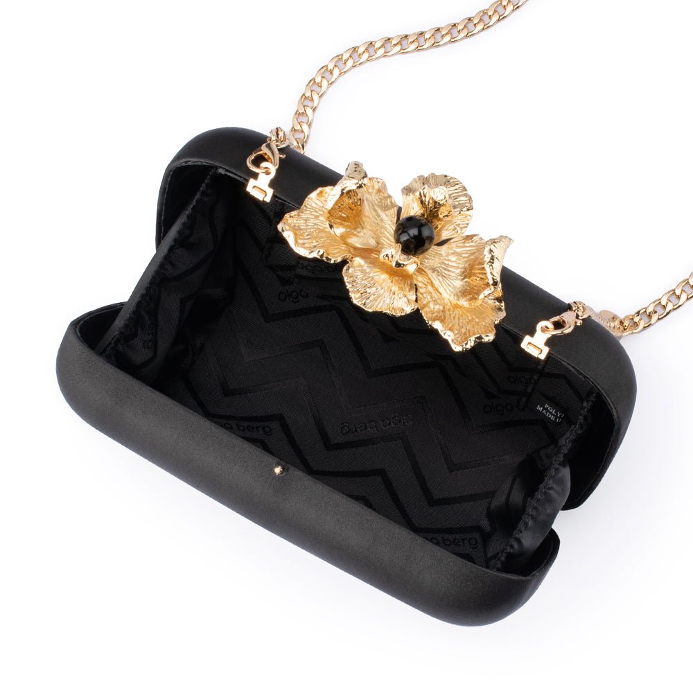 The clutch open, showing a black zigzag-patterned lining and the gold chain clipped inside