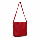 The red shoulder bag turned slightly, showing the curved seam and strap buckle.