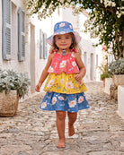 Toddler walking barefoot along a cobbled lane in the Camille tiered dress