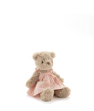 Small light brown teddy bear in a pale pink dress, sitting against white.