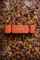 The Celebrate bon bon on top of a fruit cake studded with nuts and cherries.